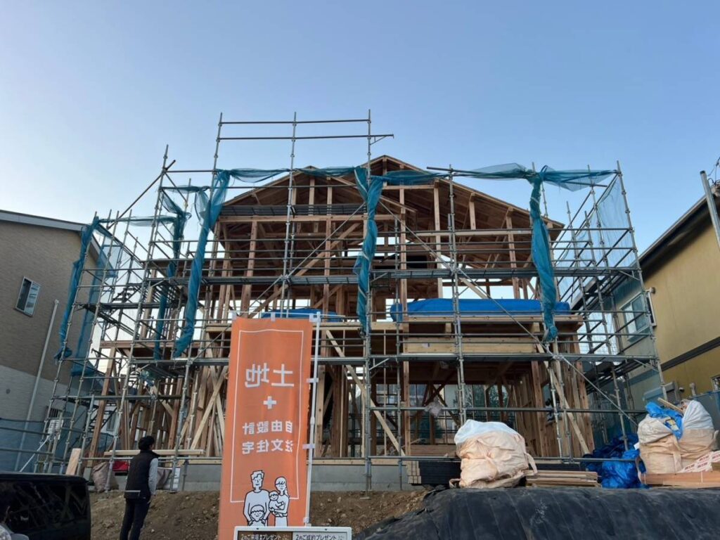 足場が組まれた新築住宅の骨組み工事と作業員